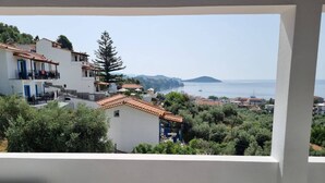 Vista costera desde un balcón con edificios, árboles y cielo despejado.