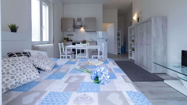 A modern living room with a sofa, a dining table, and a kitchen in the background. - Casetta di Elie - Affitti Brevi Italia (Lecco)