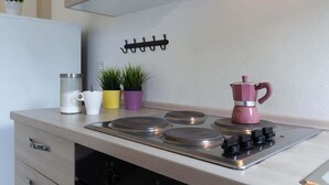 Een keuken met een fornuis, een koffiezetapparaat en een haak om spullen aan op te hangen.