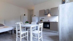 Een moderne keuken met witte kasten, een eettafel met stoelen en een koelkast.