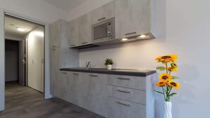 Een moderne keuken met grijze kastjes, een roestvrijstalen magnetron en een vaas zonnebloemen.