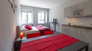 A compact hotel room with two beds, a kitchenette, and a dining area. - Appartamento Papavero - Affitti Brevi Italia (Lecco)