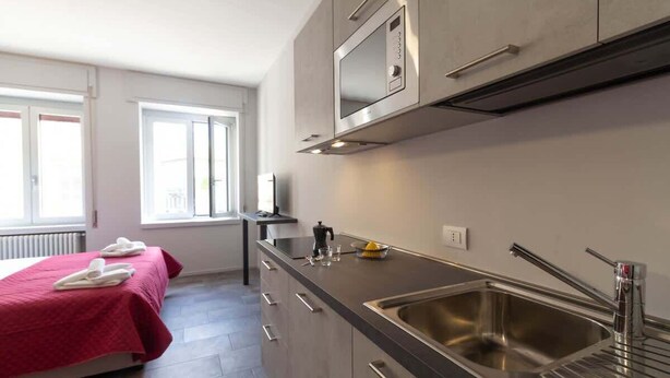 A modern kitchen with a stainless steel sink, a microwave, and a window providing natural light. - Appartamento Papavero - Affitti Brevi Italia (Lecco)