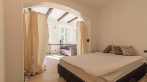A bedroom with a bed, curtains, a sofa, and a window. - Lungolago Holiday Home - Affitti Brevi Italia (Lecco)