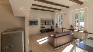 A modern living room with a sofa, a dining table, and a built-in TV. - Lungolago Holiday Home - Affitti Brevi Italia (Lecco)