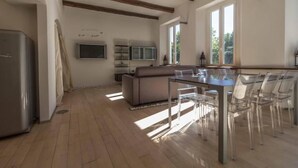 A spacious kitchen with wooden beams, a dining area with clear chairs, and a large window providing natural light. - Lungolago Holiday Home - Affitti Brevi Italia (Lecco)