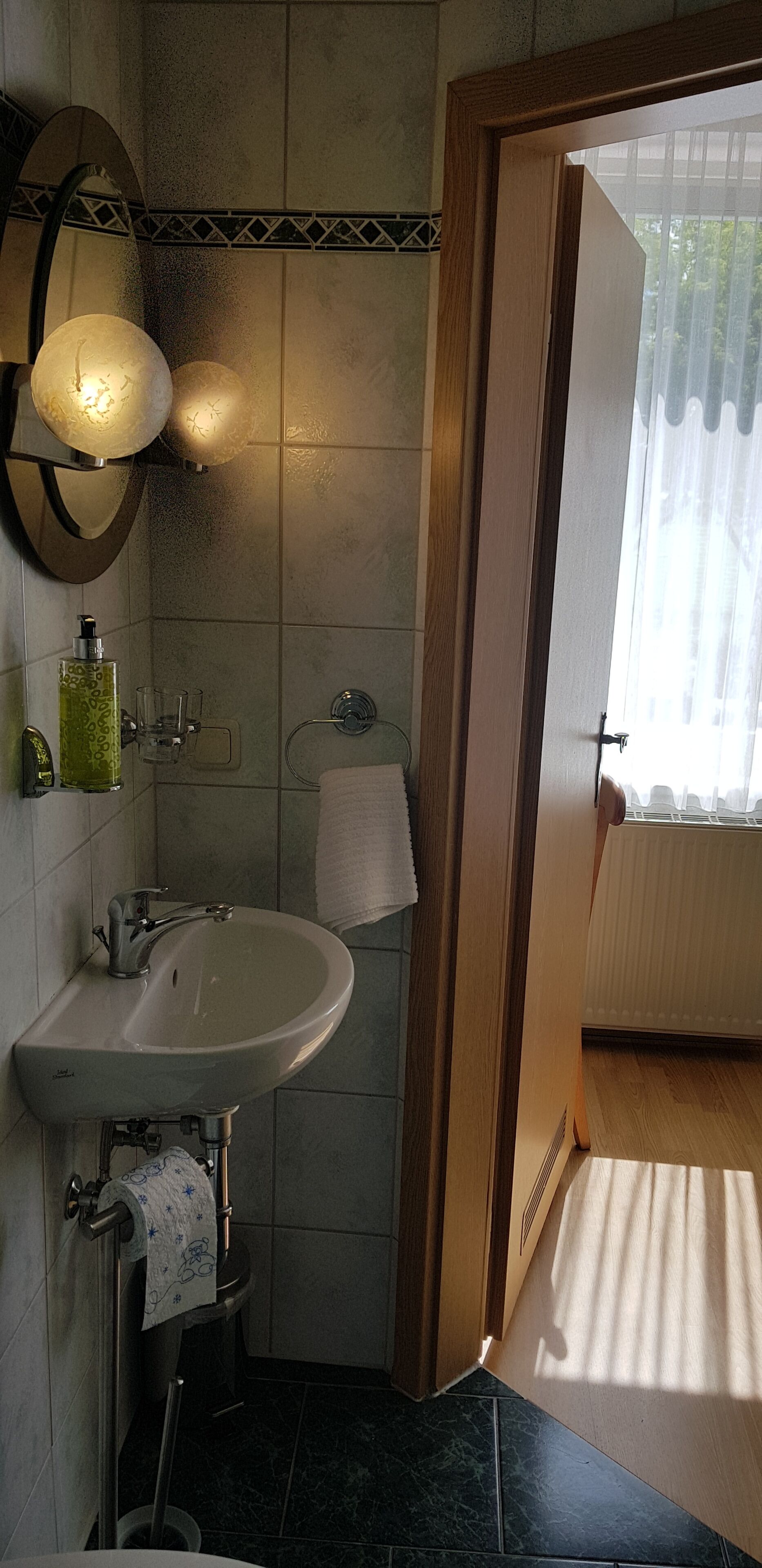 Een badkamer met een wastafel, spiegel, handdoekhouder en douche.