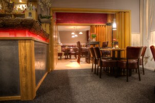 Um saguão de hotel com balcão de recepção, área de estar e espaço para refeições.