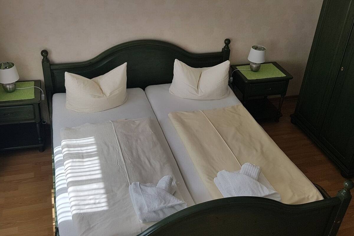 Un lit double avec deux oreillers, une table de chevet avec une lampe et une armoire.
