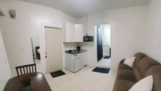 A compact living space with a kitchenette, a dining area, and a seating area. - #20 Marjory’s in-law suite (Tampa)