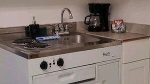 A compact kitchen with a stove, sink, and coffee maker. - #20 Marjory’s in-law suite (Tampa)