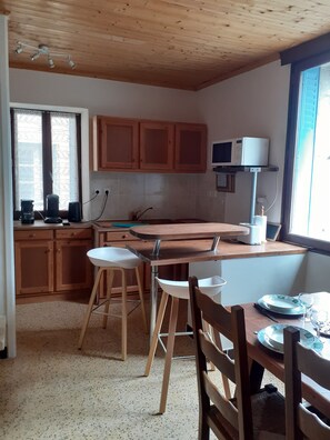 A kitchen with wooden cabinets, a microwave, and a window with curtains.