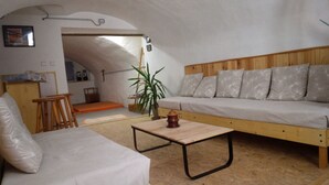 Ein gemütliches Zimmer mit einer Holzsofa, einem kleinen Holztisch, einem Stuhl und einer Topfpflanze.