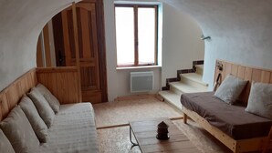 Ein gemütliches Zimmer mit einer Holzdavonia, einem kleineren Bett, einem Tisch und einem Fenster mit Blick auf eine Treppe.