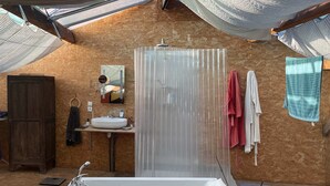 Ein Badezimmer mit einer Badewanne, einem Waschbecken und einem Spiegel. Es gibt einen Holzschrank und einen Handtuchhalter mit Handtüchern.