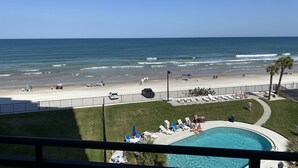 Vista a la playa desde un balcón con vista a una piscina y la zona de playa.
