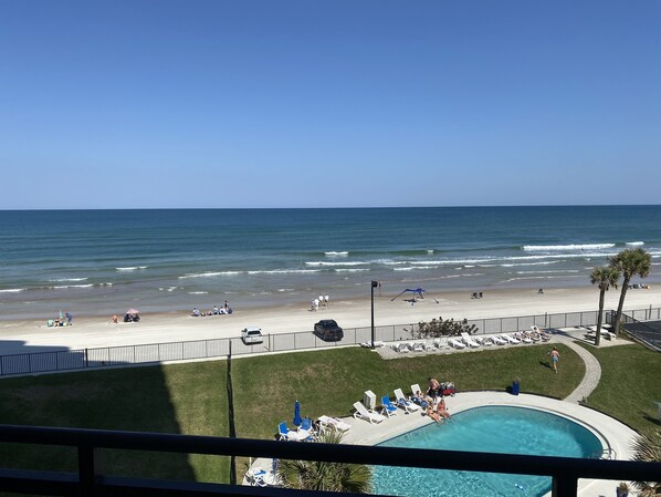 Enjoy the ocean view from our beachfront hotel, featuring a pool, lounge chairs, and umbrellas.