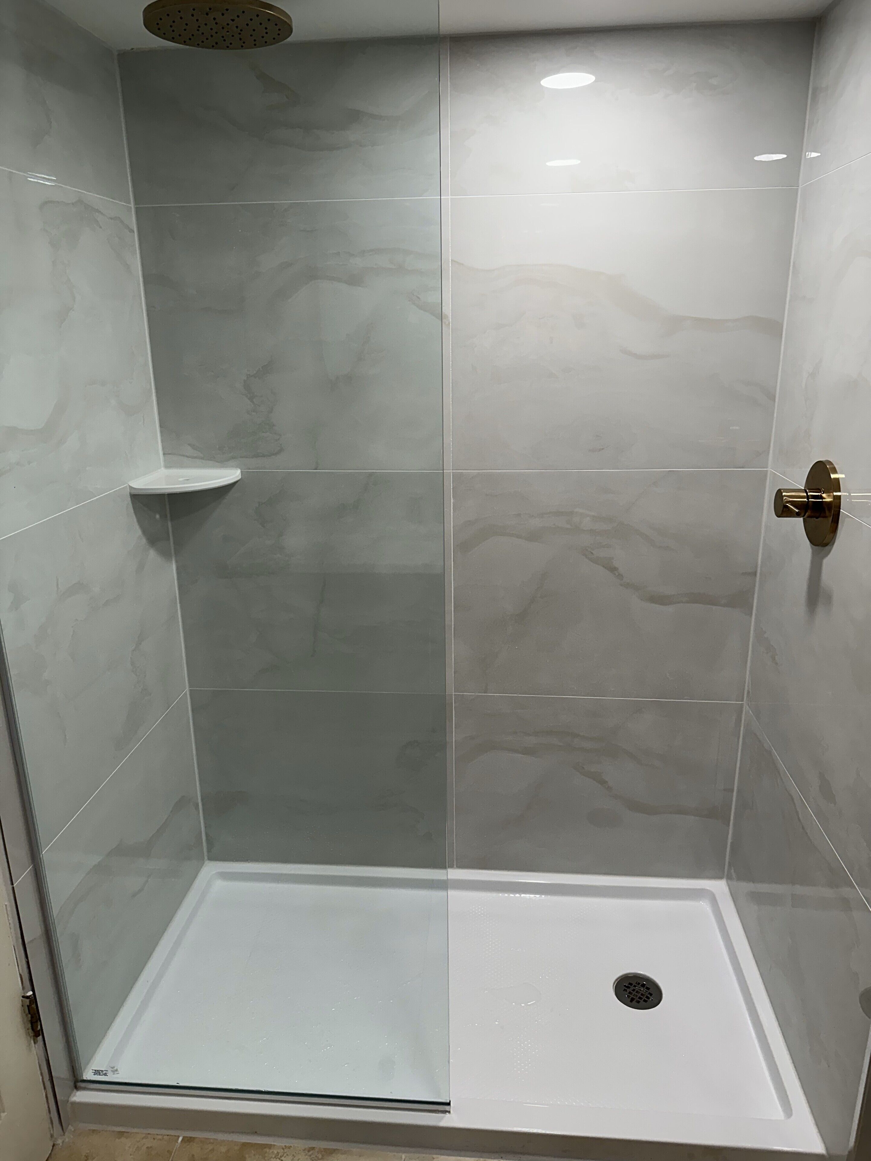 Ducha con mampara de vidrio, lavabo blanco y ducha.