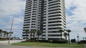 Un edificio moderno y alto, con múltiples balcones y techo plano.