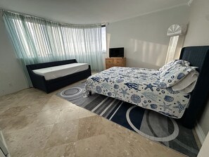 Relax in this inviting bedroom with a large bed, sofa bed, and TV on a stand.