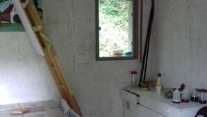 Una habitación con una cama, un ventanal pequeño, un escritorio y una silla.