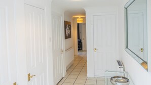 Ein Flur mit weißen Türen, einem Glastisch mit Schale und einem Spiegel an der Wand.
