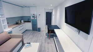 A modern apartment with a kitchen, dining area, and a large TV. - Modern Studio Apartment Gibraltar (Gibraltar)