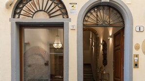 Entrada de hotel con fachada de piedra, puerta de madera y una escalera que lleva al interior.