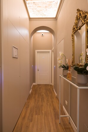 A hallway with a wooden floor, a white door at the end, and a mirror on the right. - Atelier delle Grazie (Florence)