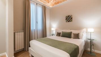 Una habitación de hotel con una cama grande, dos lámparas de noche, un radiador y un techo con diseño de ladrillo.