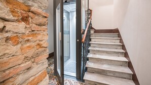 Una escalera con barandilla, un vidrio que da a una habitación y un piso con diseño.