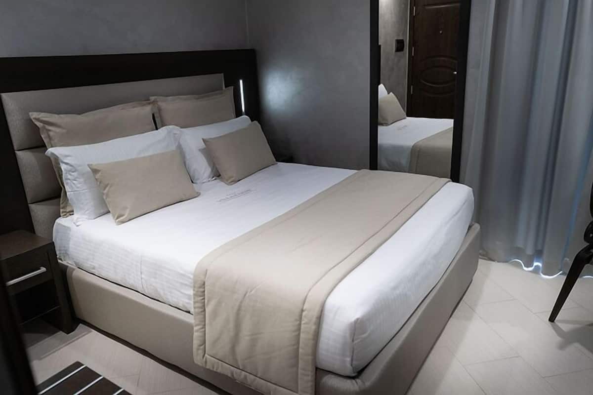 Une chambre d’hôtel moderne avec un grand lit, une table de chevet et un miroir.