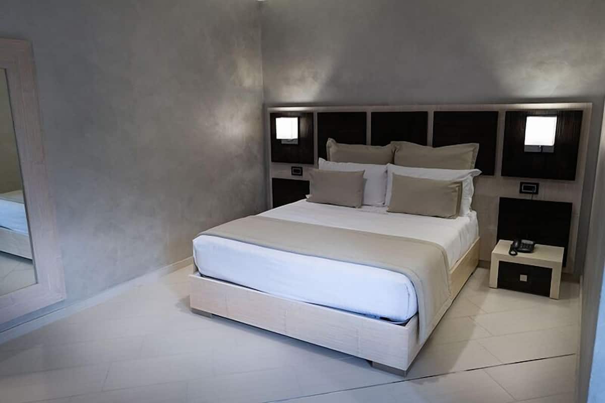 Une chambre à coucher moderne avec un grand lit, des tables de chevet et un miroir.