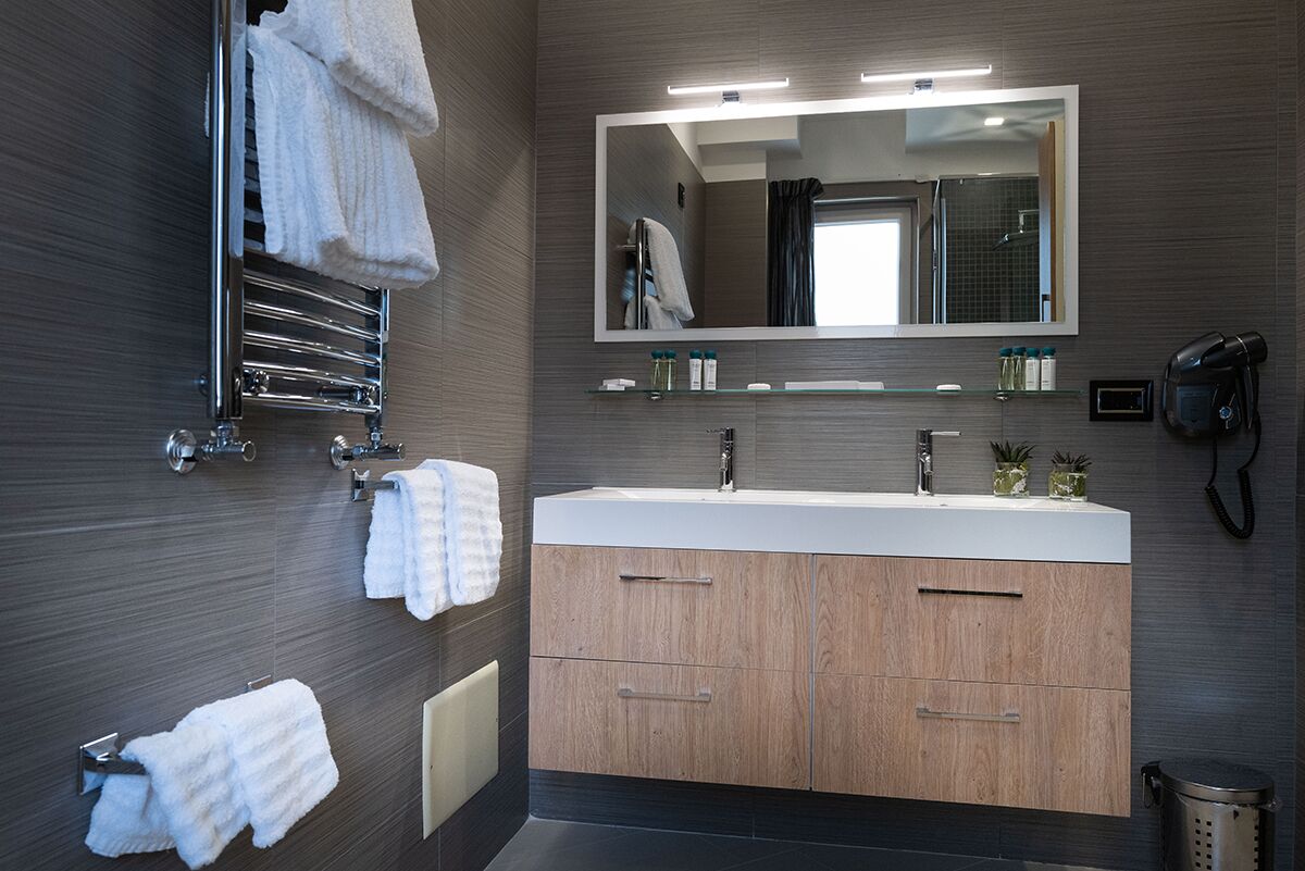 Een moderne badkamer met een grote spiegel, een wastafel en een handdoekrek.