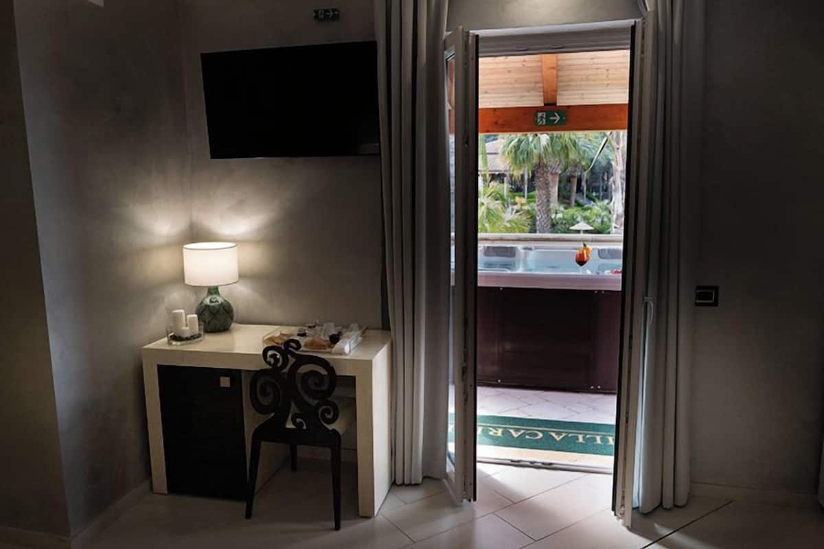 Une chambre d’hôtel équipée d’un bureau, d’une chaise, d’une lampe et d’un téléviseur fixé au mur.