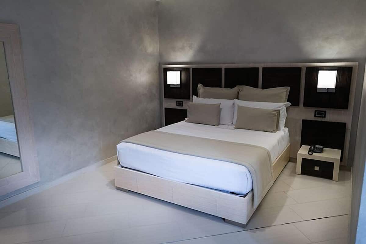 Une chambre à coucher moderne avec un grand lit, des tables de chevet et un miroir.