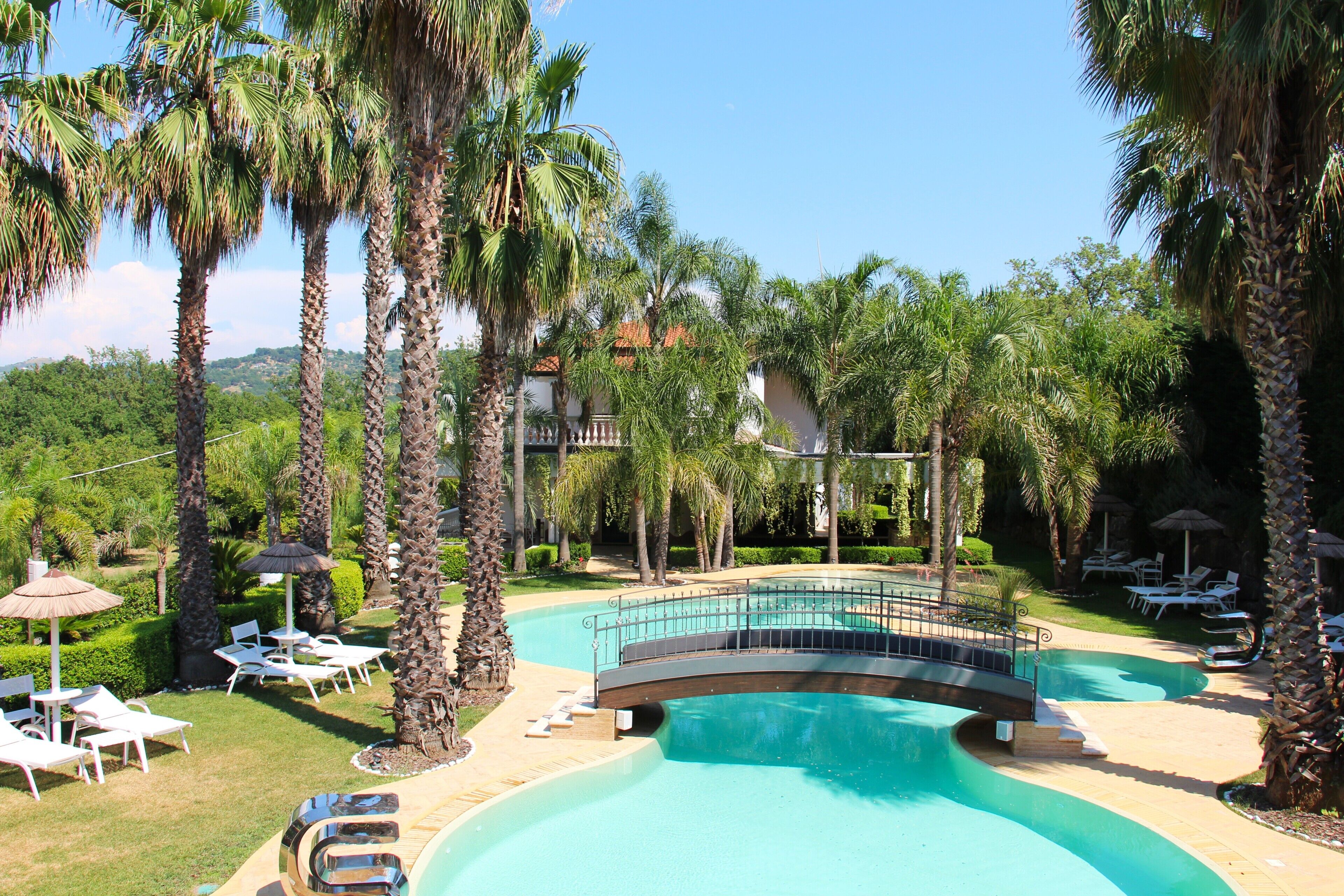 Un resort con piscina, sillas de descanso y palmeras.