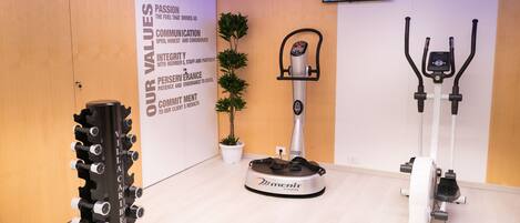 A fitness area with a rowing machine, an elliptical trainer, and a stationary bike.