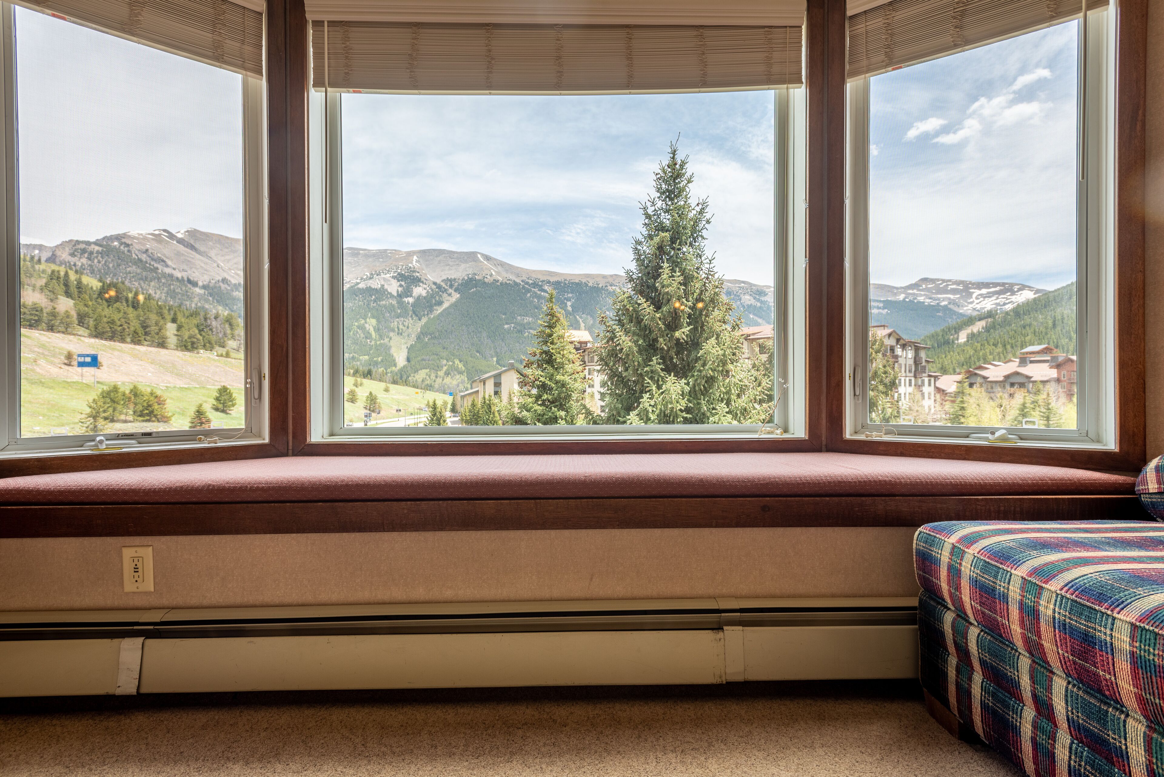 A room with a large window seat overlooking a mountainous landscape.