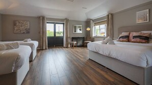 Une chambre spacieuse avec un grand lit, deux petits lits, un bureau et une cheminée.