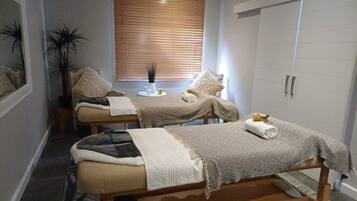 Relax in this serene spa room with two massage tables, a comfortable seating area, and a wardrobe for your belongings.