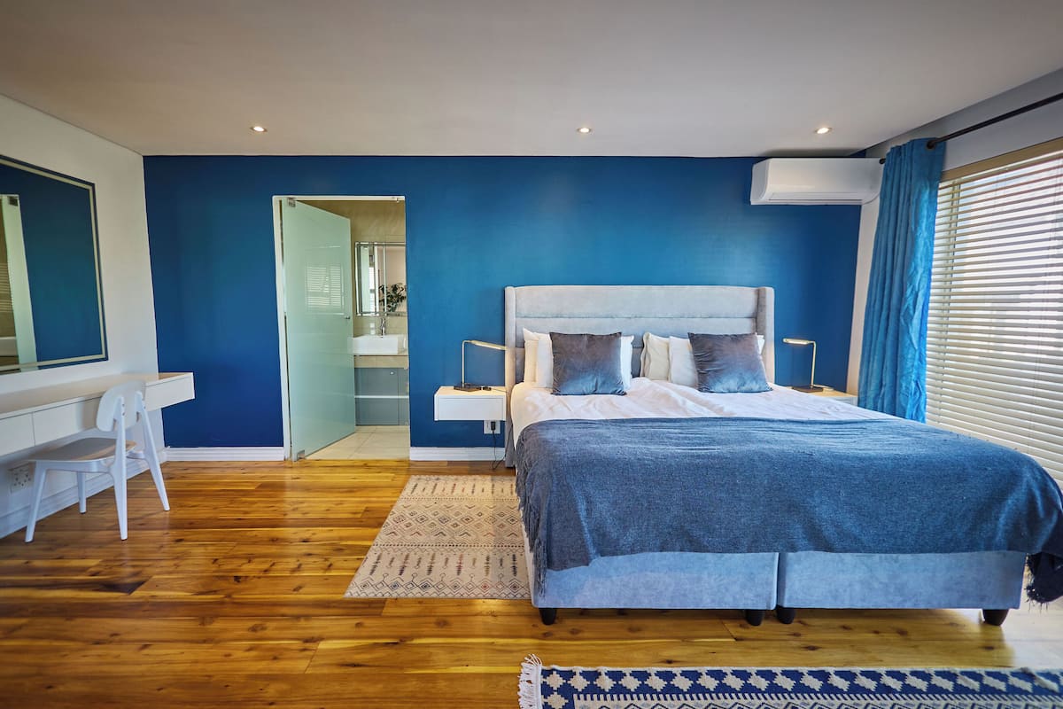 A modern bedroom with a large bed, a desk, and a chair.