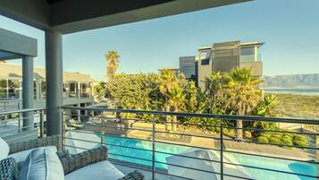 A rooftop pool area with lounge chairs, a swimming pool, and a view of a modern building and mountains.
