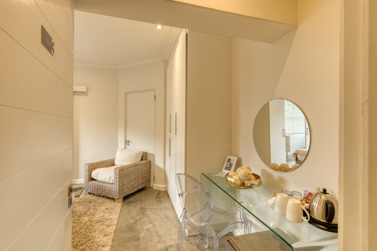 A modern bathroom with a glass vanity, a wicker chair, and a mirror.