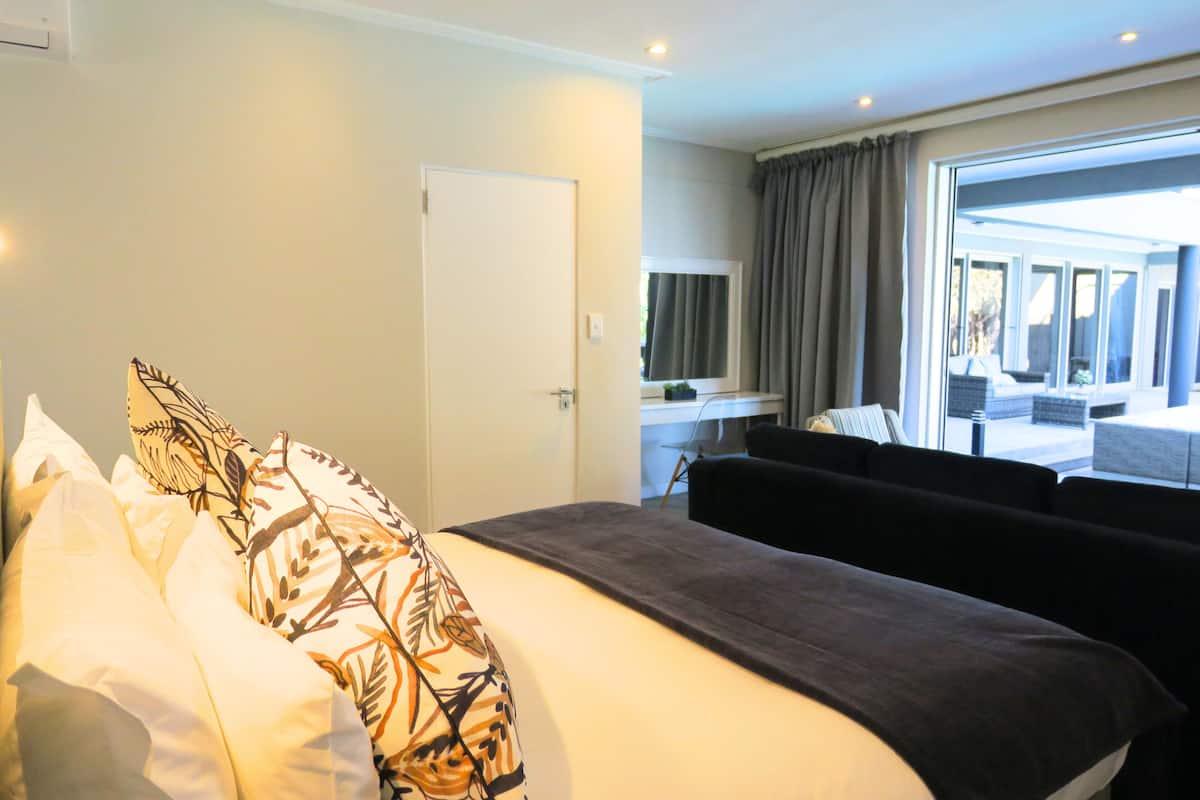 A hotel room with a bed, a window with curtains, a desk, and a view of the outside.
