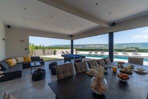 A modern outdoor lounge area with a pool, seating, and a dining table with food and drinks. - Luxury Villa Madre with heated Mineral pool, Whirlpool, Outdoor Gym (Zmijavci)