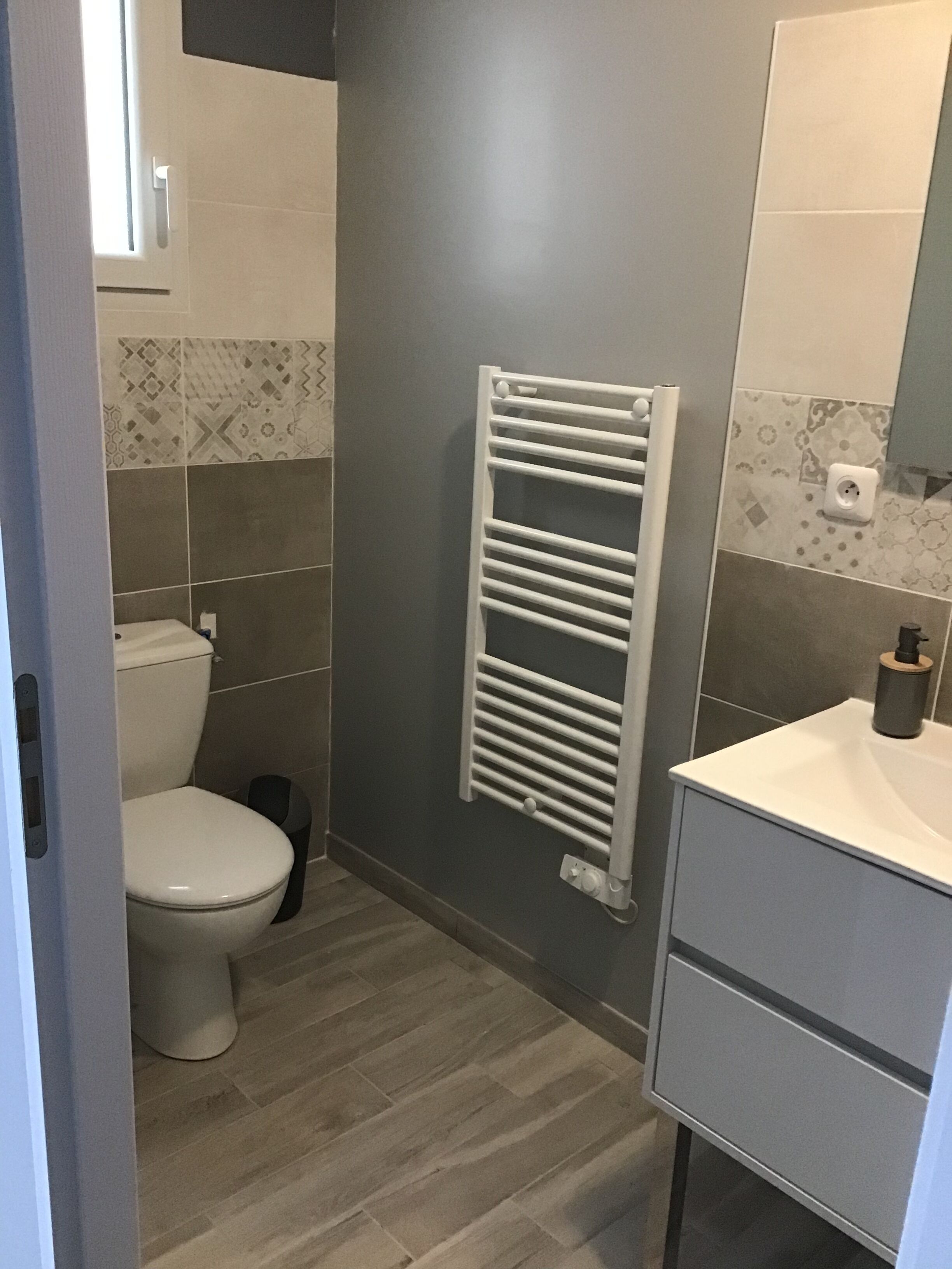 Une salle de bain moderne avec des toilettes, un porte-serviettes blanc et un lavabo avec un miroir.