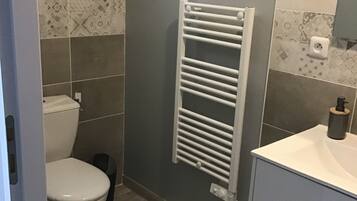 Une salle de bain moderne avec des toilettes, un porte-serviettes blanc et un lavabo avec un miroir.