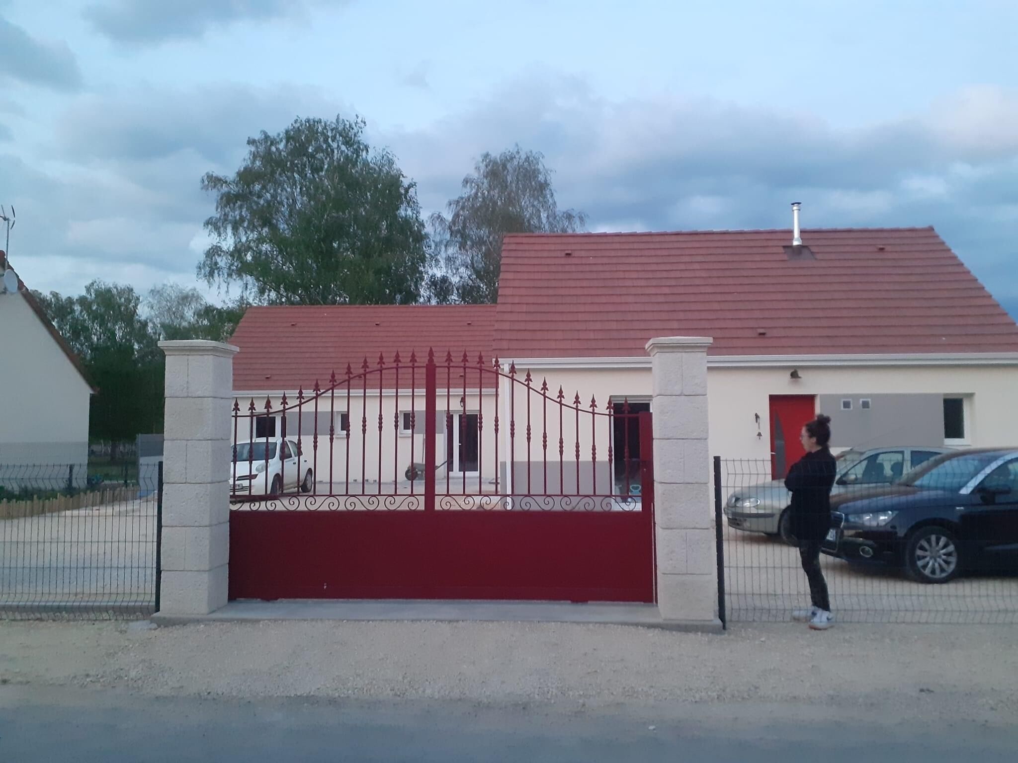 A gated entrance to a building with a red roof and a white facade.