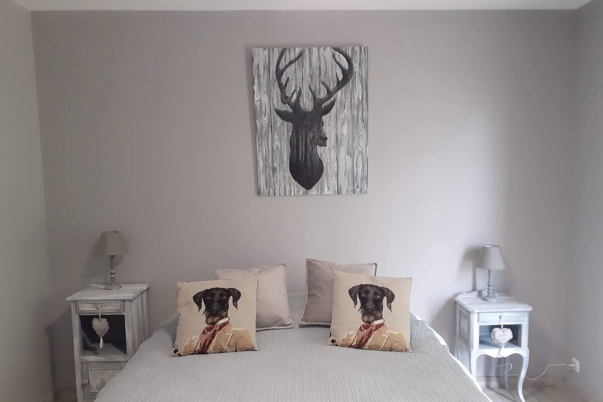 A bedroom with a large bed, two nightstands, and a wall-mounted deer head artwork.